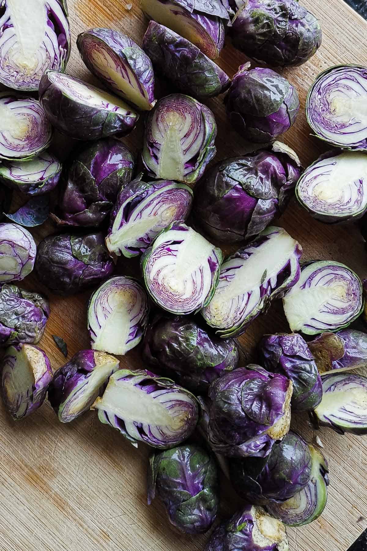 Cut up purple brussels sprouts on a bamboo cutting board.