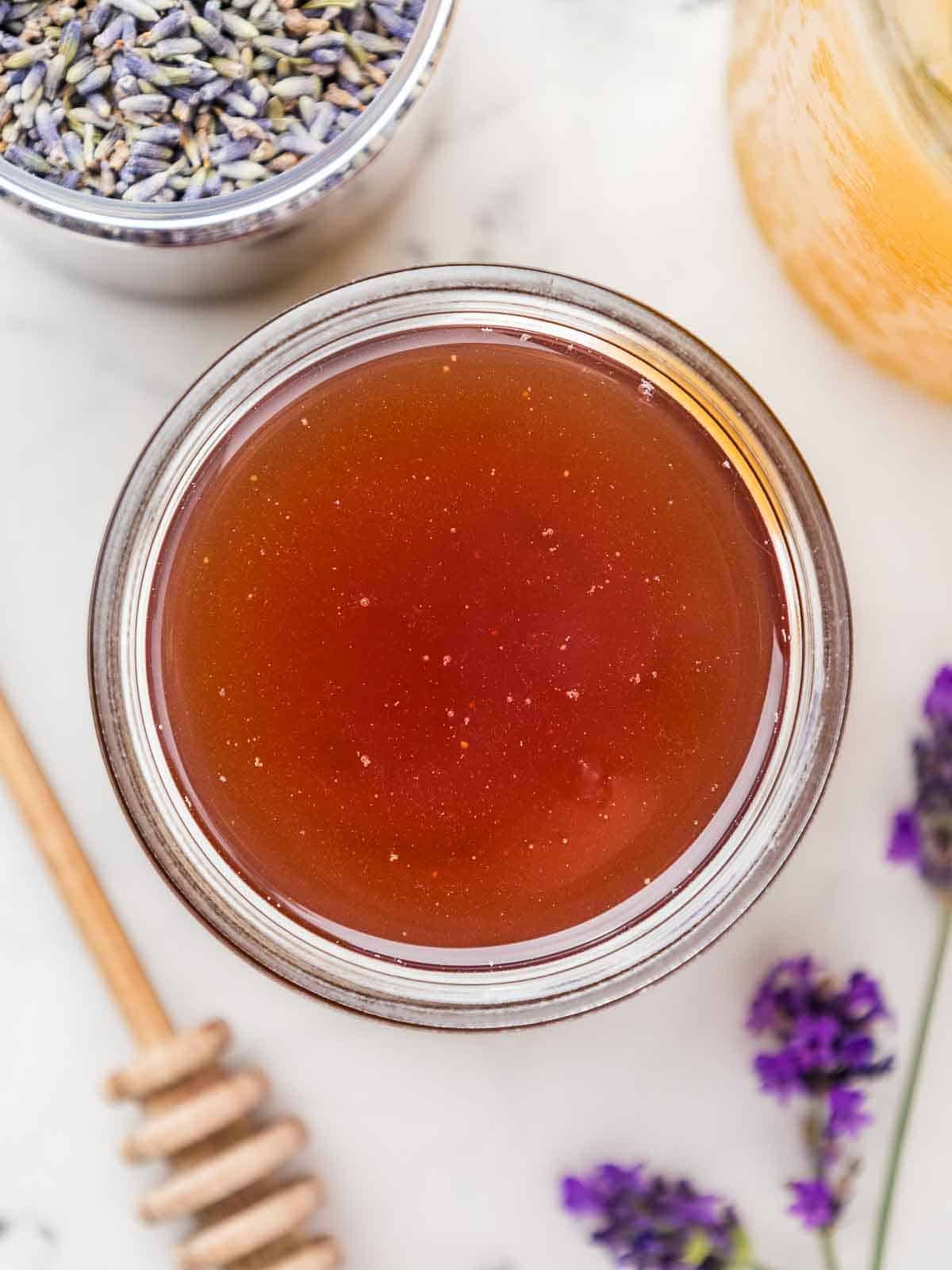 A jar of vegan honey lavender syrup taken from above, with lavender flowers around.