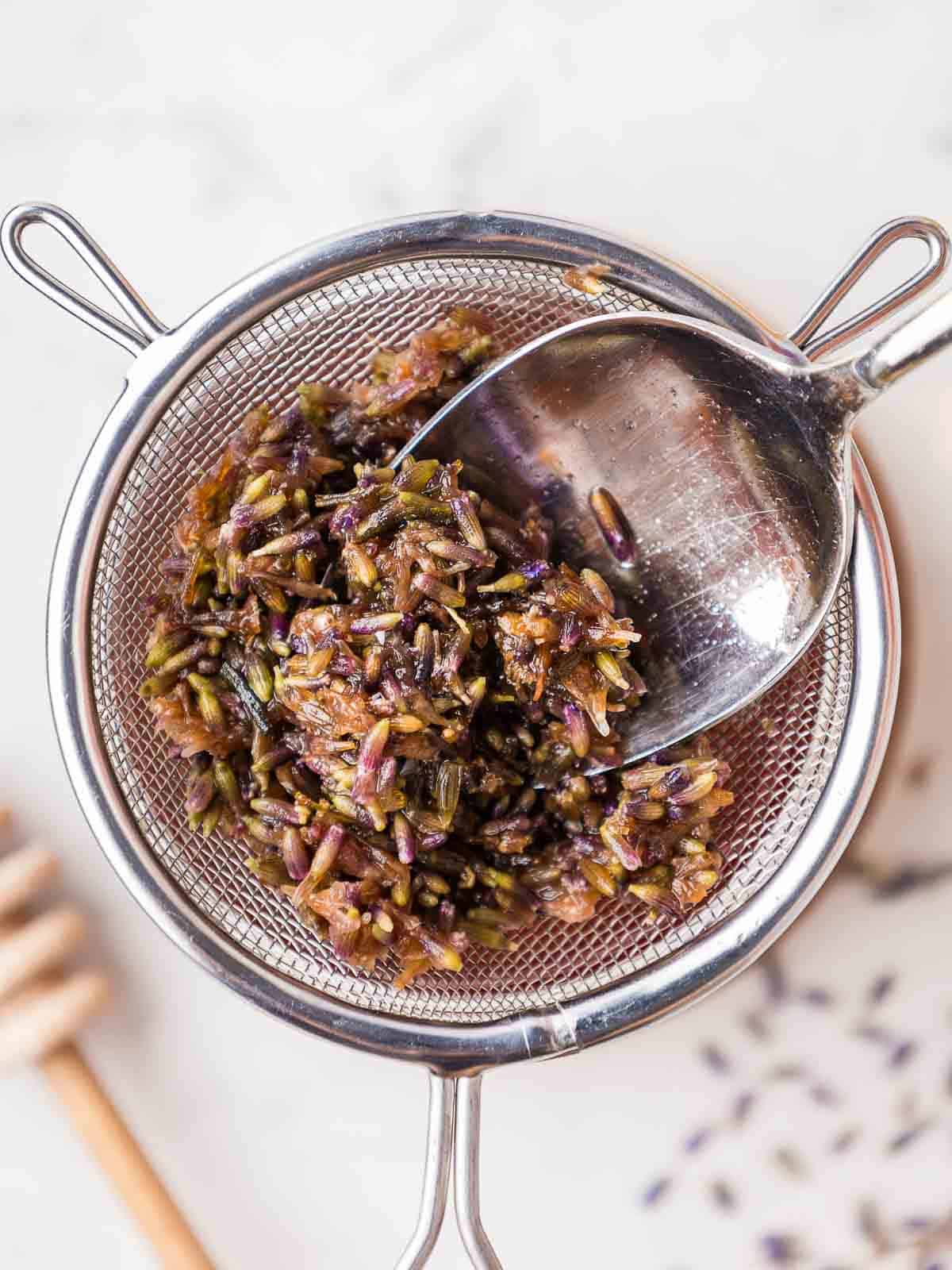 Using the back of a spoon to press the lavender to infuse more lavender flavor into the honey.