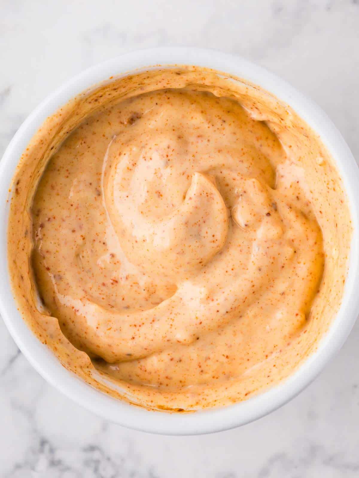 Spicy garlic chili mayo sauce in a white ramekin, taken from above.