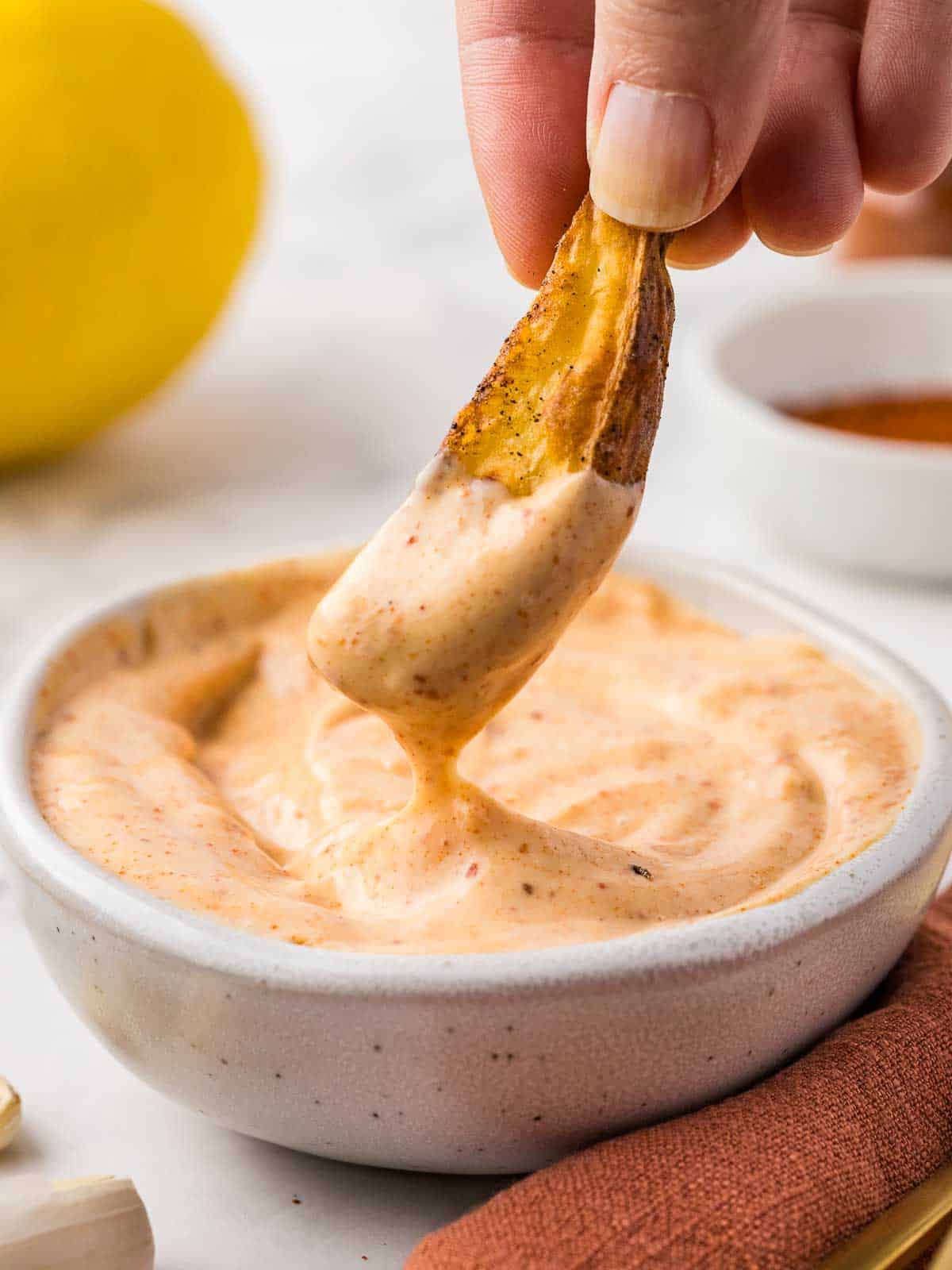 Dipping a French fry into spicy garlic aioli sauce.