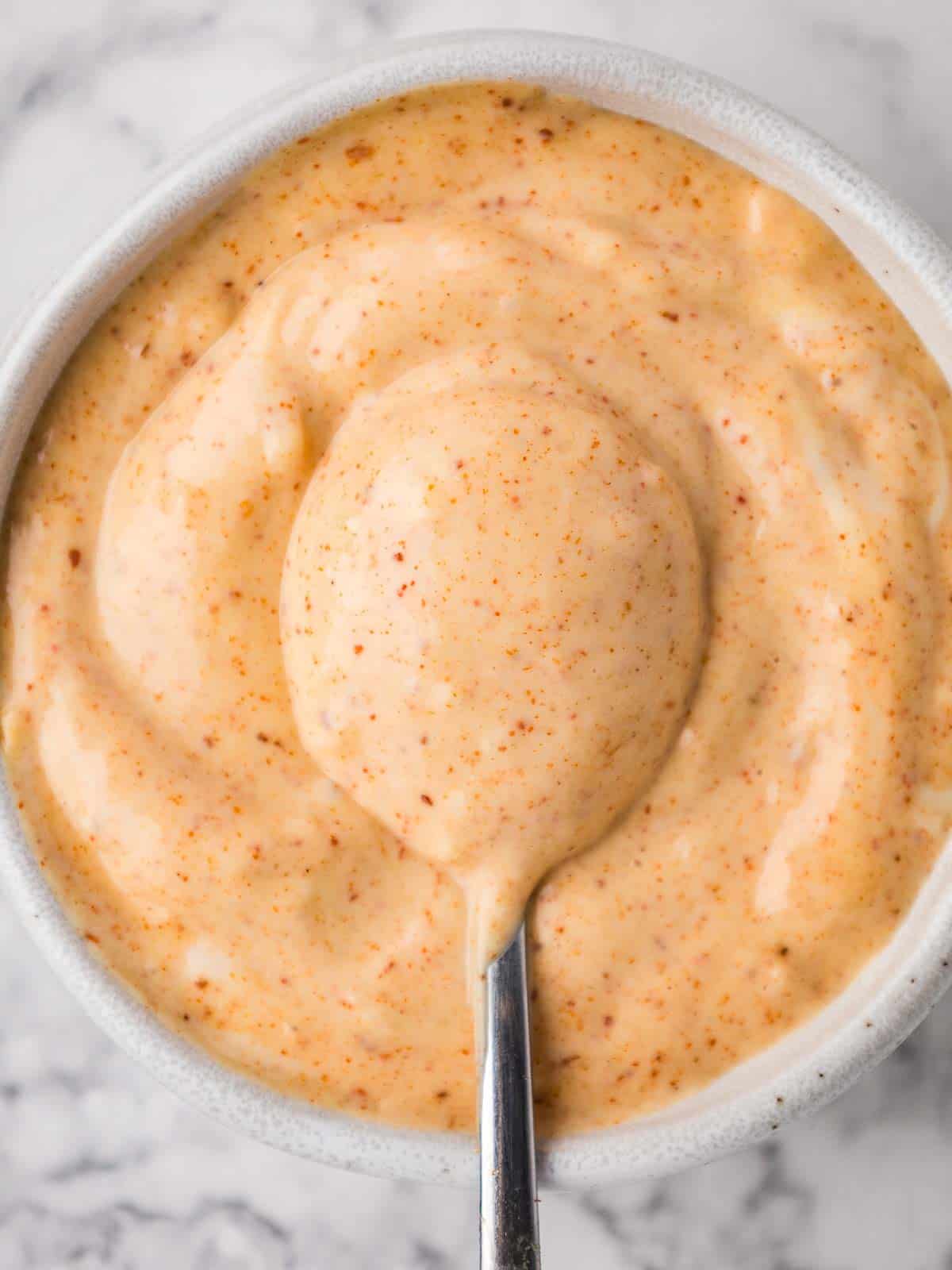 Close-up of spicy garlic chili aioli with a spoonful of it in the middle.