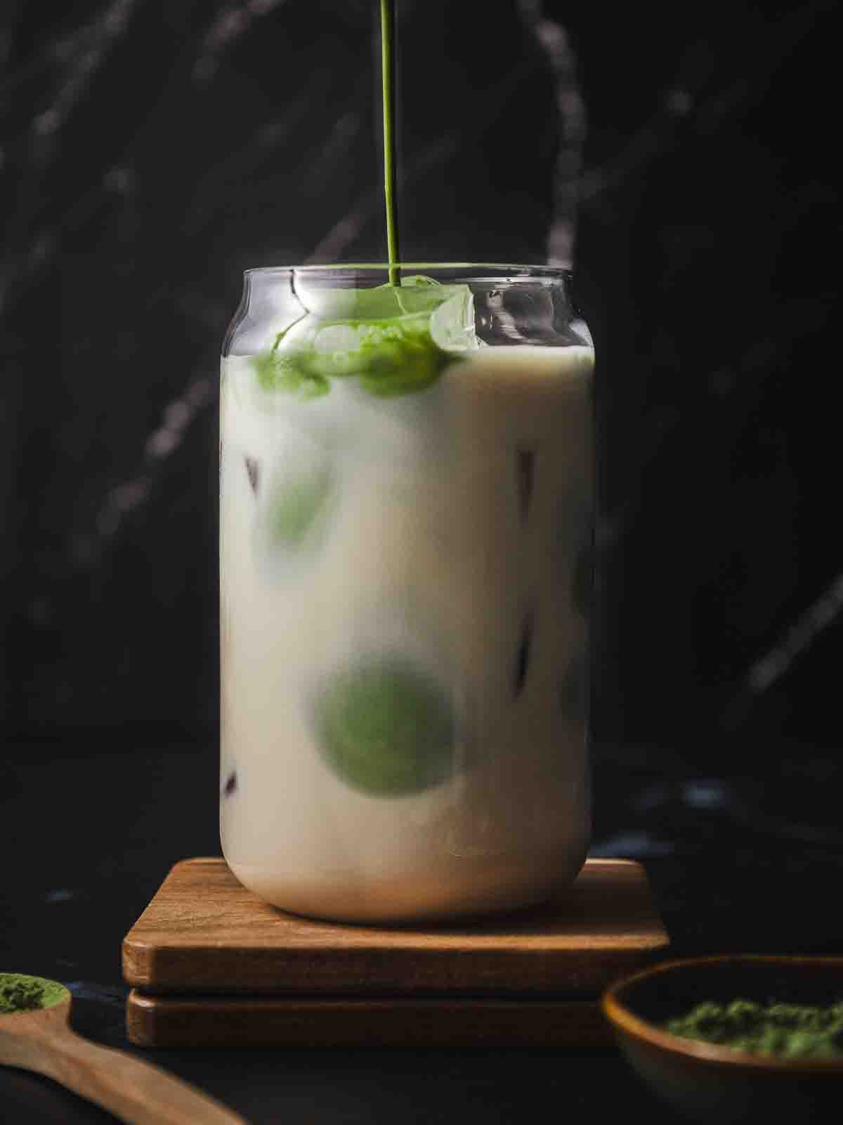 Pouring the matcha shot into a glass of milk with ice cubes.