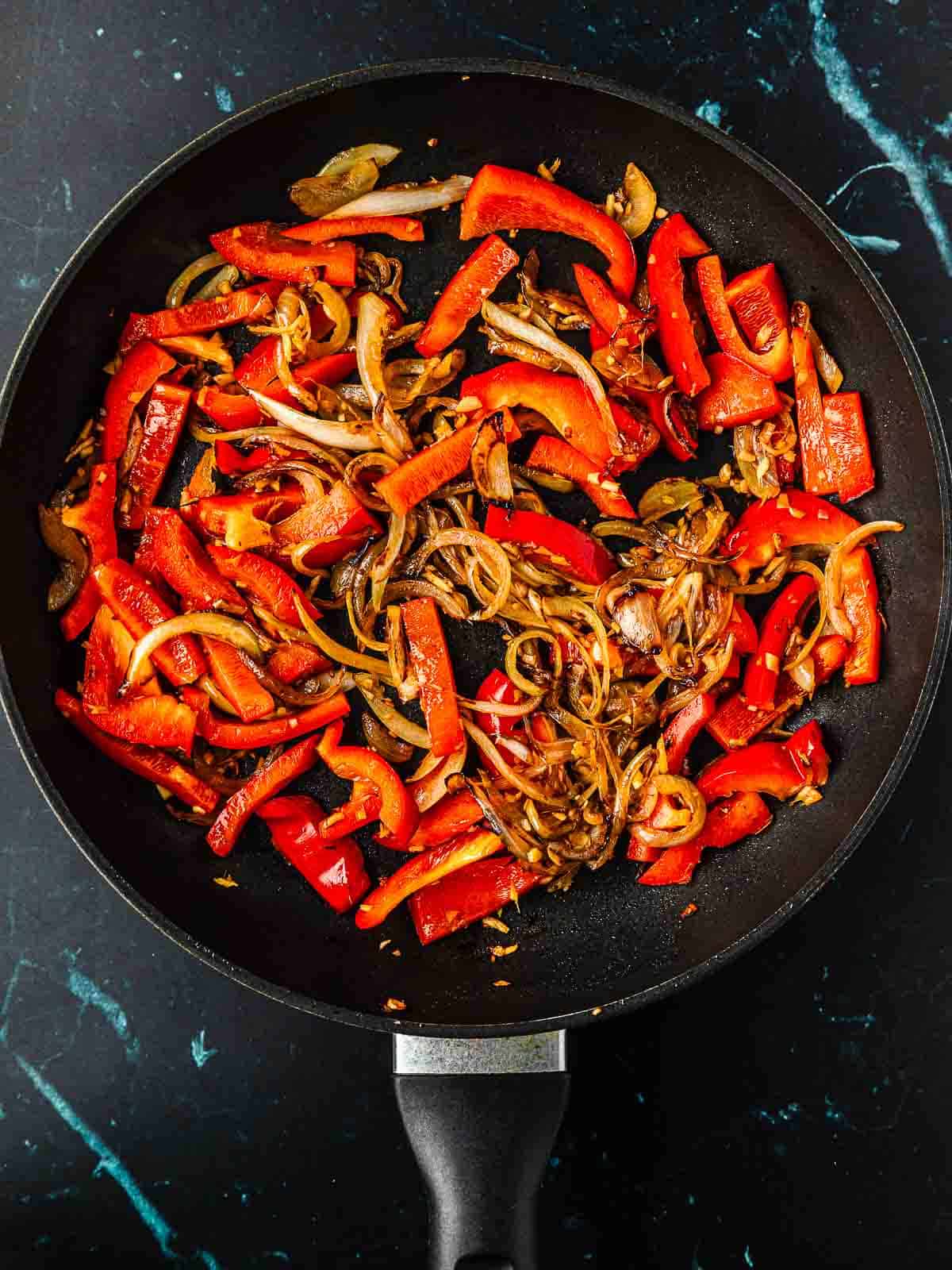 A pan of sauteed bell pepper, julienned carrot, and edamame beans.