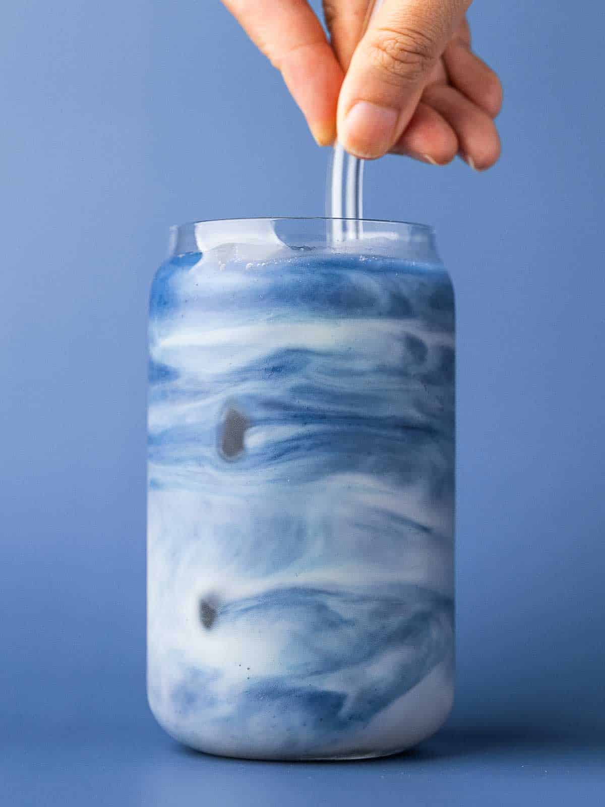 Blue matcha latte being stirred to create a marbled look.