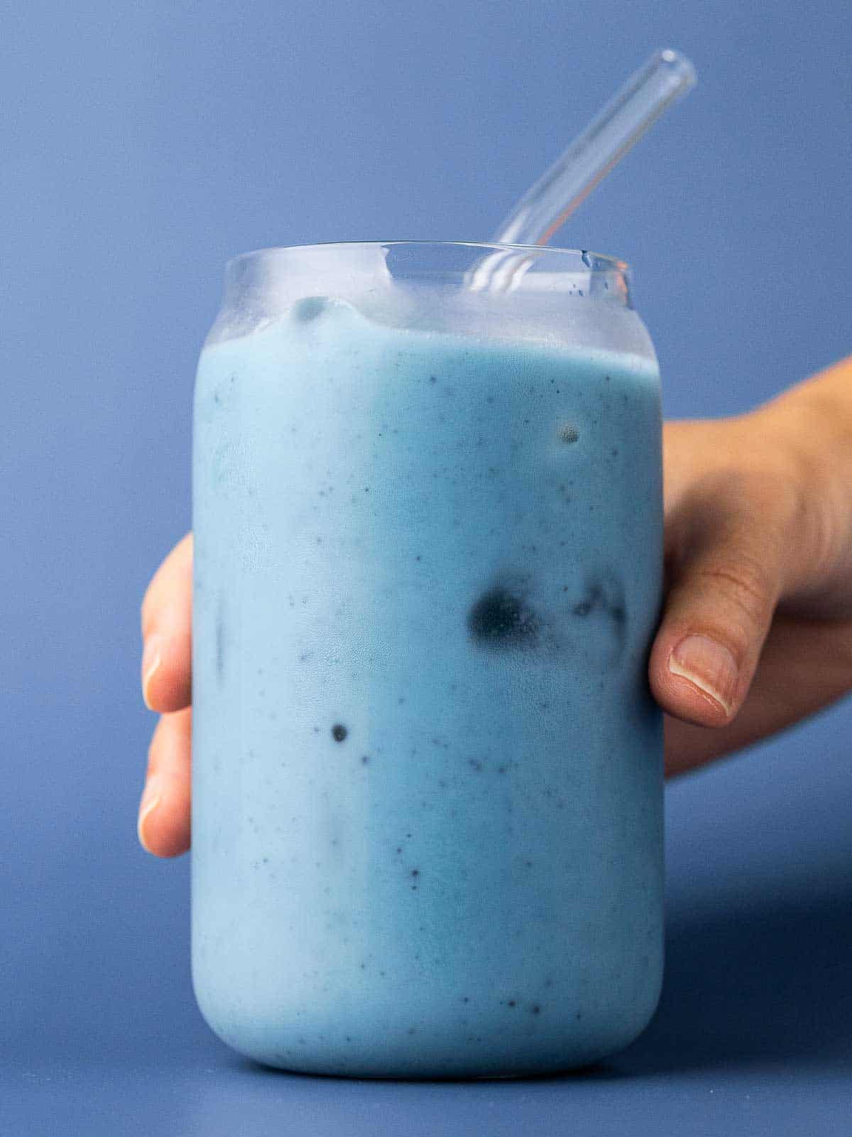 Someone grabbing a glass of blue matcha latte.