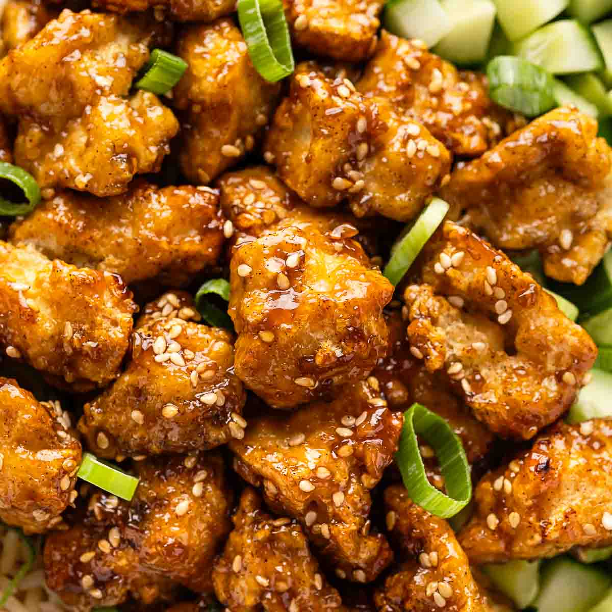 Crispy sticky tofu bowl, garnished with sesame and scallion, taken close-up.