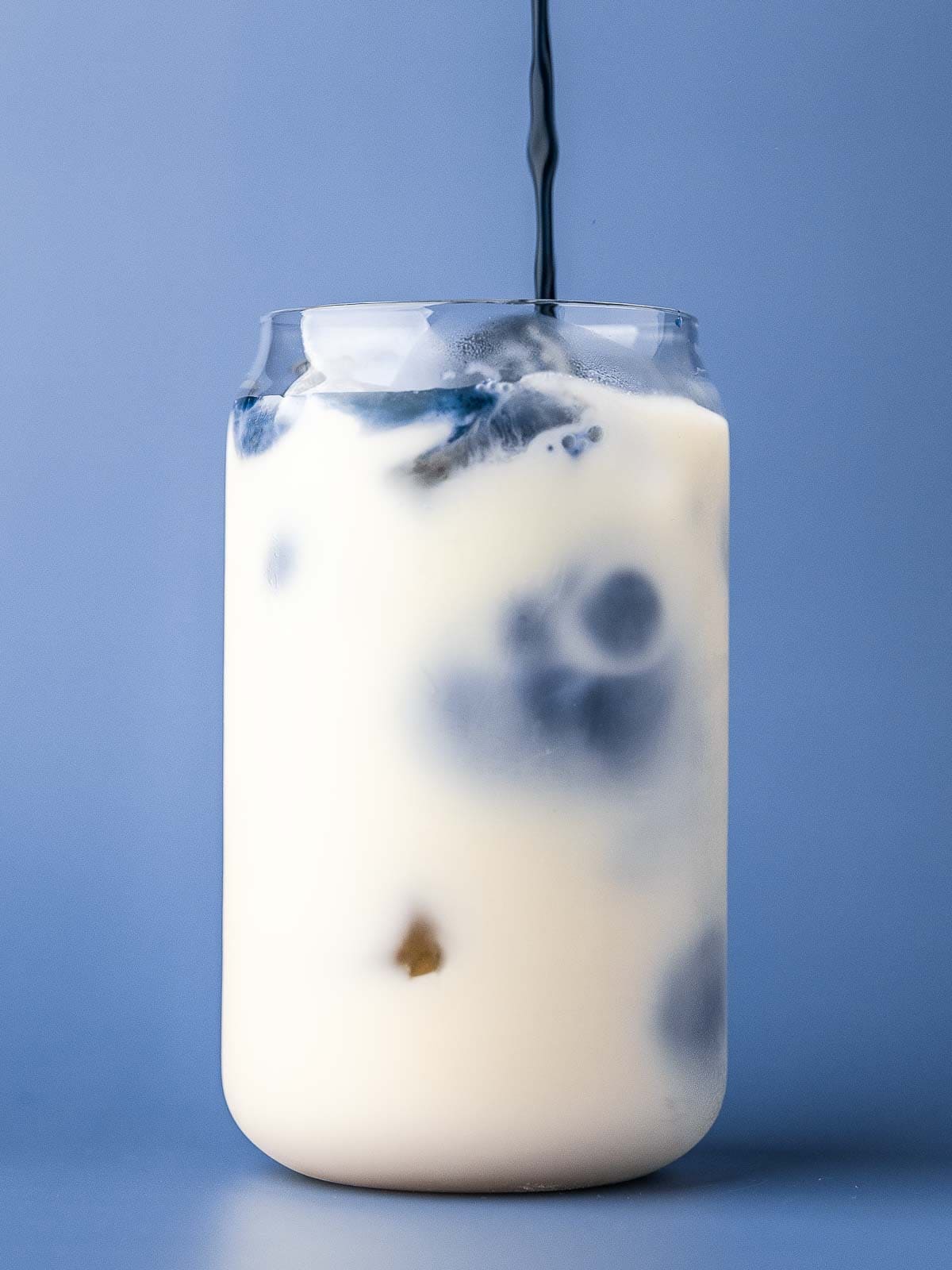 Pouring the blue tea into a glass or iced milk.